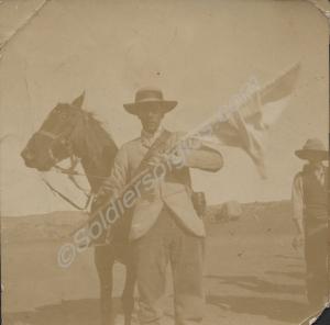 Man in civilian dress holding flag standing beside