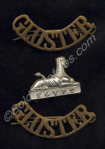 Two brass shoulder titles and white metal collar d