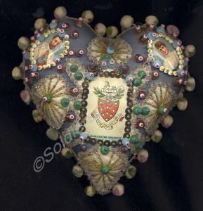 Pin cushion decorated with a card badge of the Glo