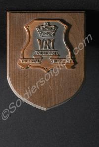 Small wooden shield-shaped plaque with a bronze ba