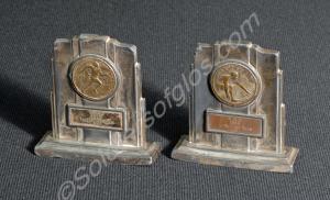 Two sporting medals mounted on white metal stand.