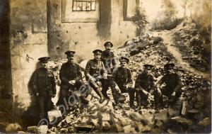 Group of soldiers sitting among ruins.  1/4th Batt