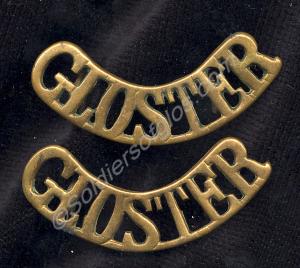 Two brass shoulder titles with backing plates. Pro