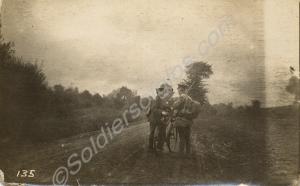 Two soldiers with a bicycle standing in a country