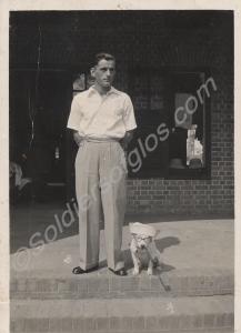 Unidentified man and dog, the dog wearing a hat an