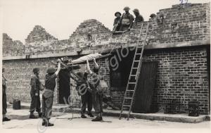 Soldiers hoisting a stretcher down from a wall. Re