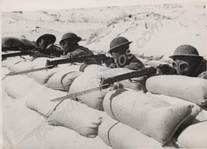 Soldiers in gas masks manning a sandbagged trench.