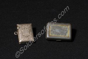 Two match holders, one is silver with a flip-top l