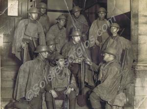 Soldiers in helmets, service dress and gas capes.