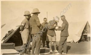 Group of soldiers examining a centipede in a mug.