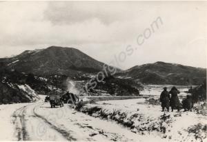 View of road with vehicles and troops, mountains i