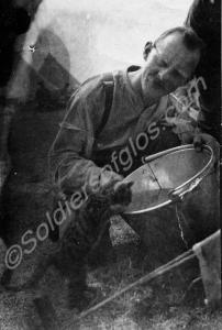 Soldier with kitten drinking from pail. 12th Batta