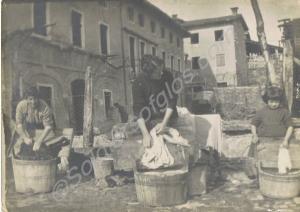 Women and girl scrubbing clothes in street. Probab