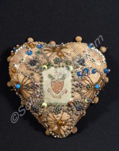 Pin cushion decorated with pins, beads, and the cr
