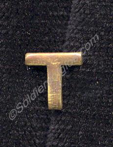 Brass letter "T" worn below officer's sphinx colla